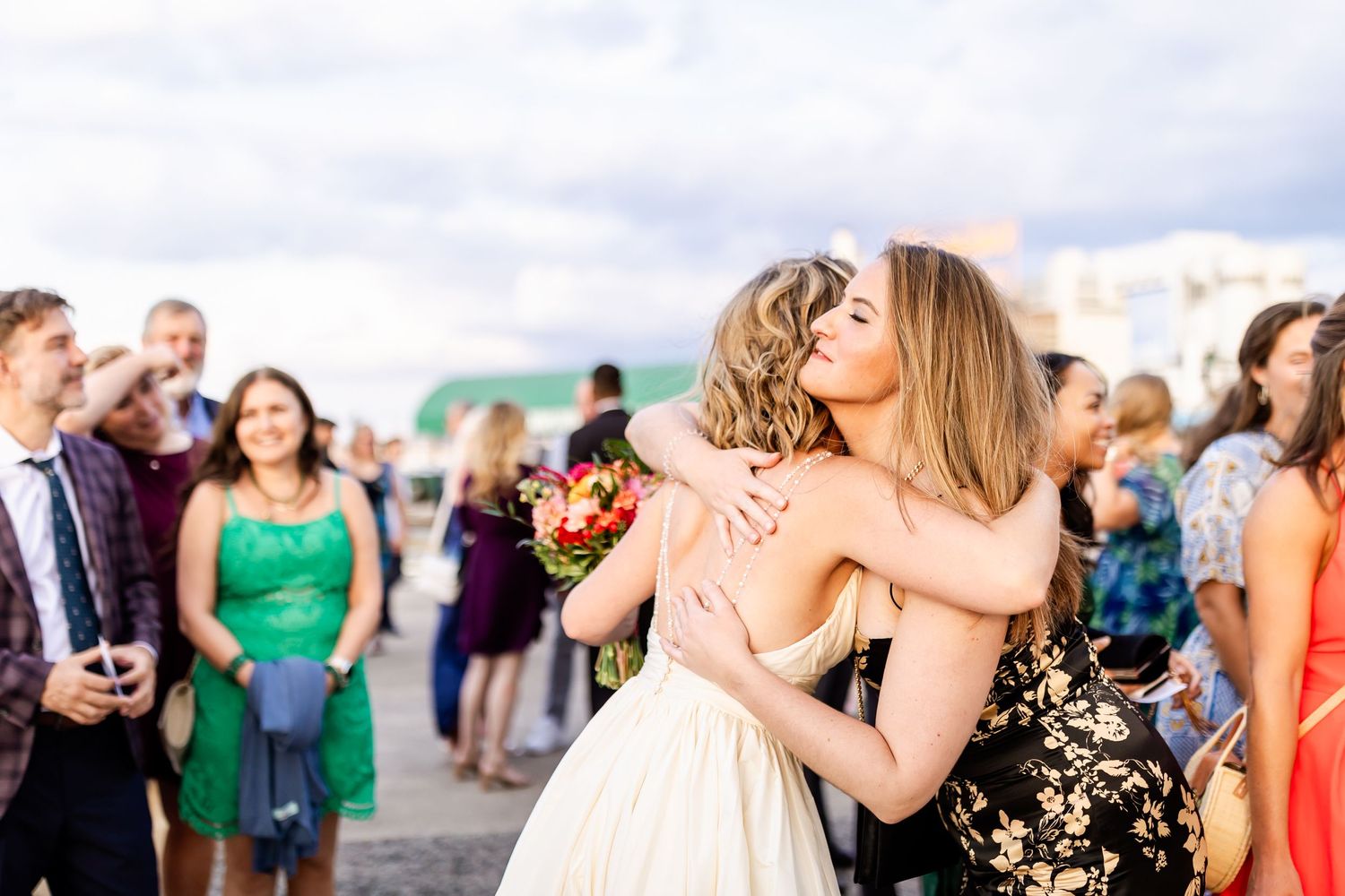 Wedding guests celebrate with warm embraces during an outdoor reception.