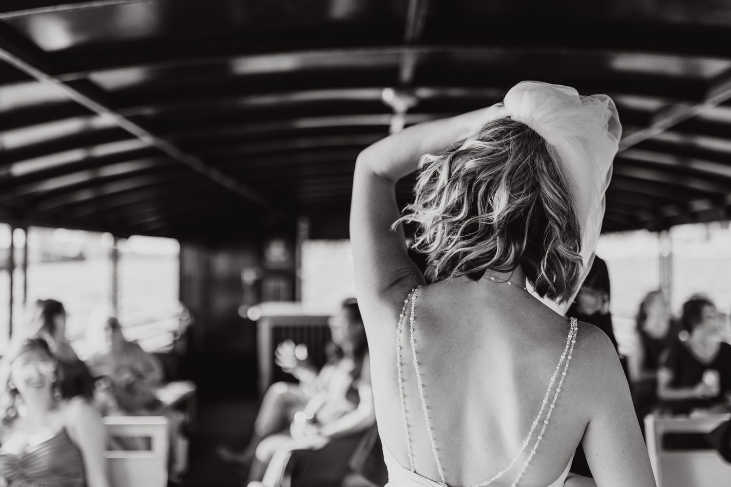 Black and white photo of person in formal dress with bare back at an indoor event.