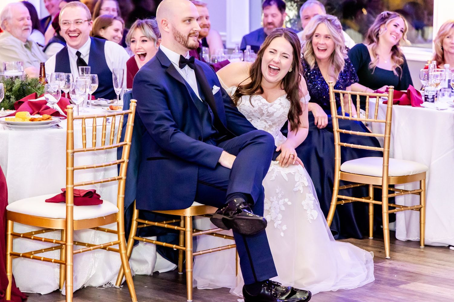 Wedding guests laughing and enjoying themselves at a reception with gold chairs and festive atmosphere.