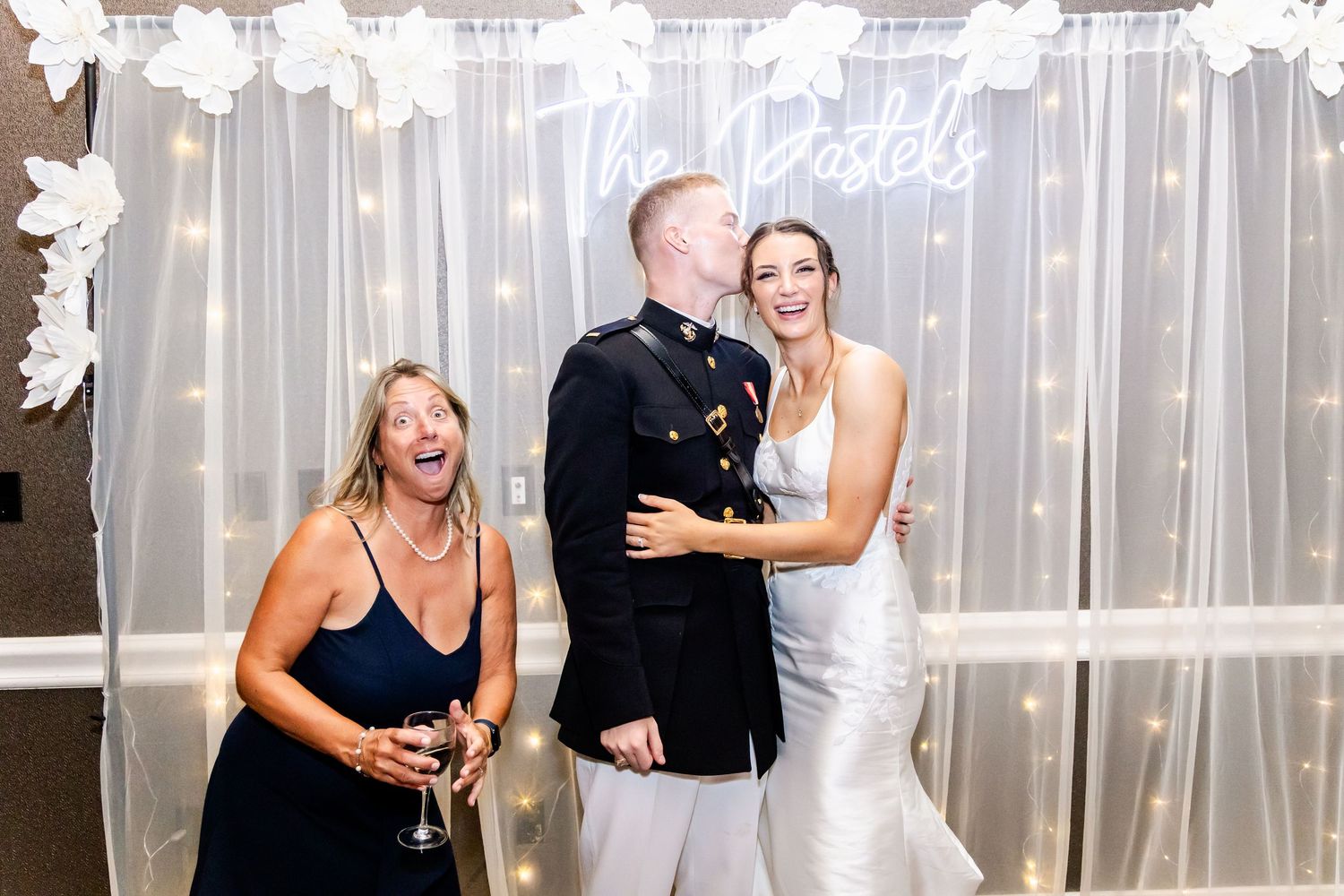 Wedding reception with illuminated backdrop and guests celebrating on the dance floor.