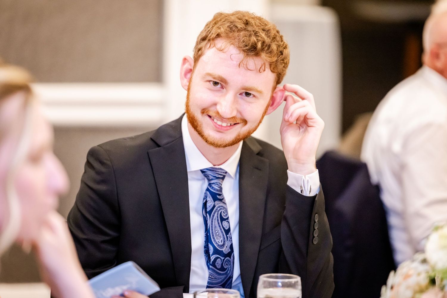 Wedding guests share laughter and conversation during an indoor reception celebration.