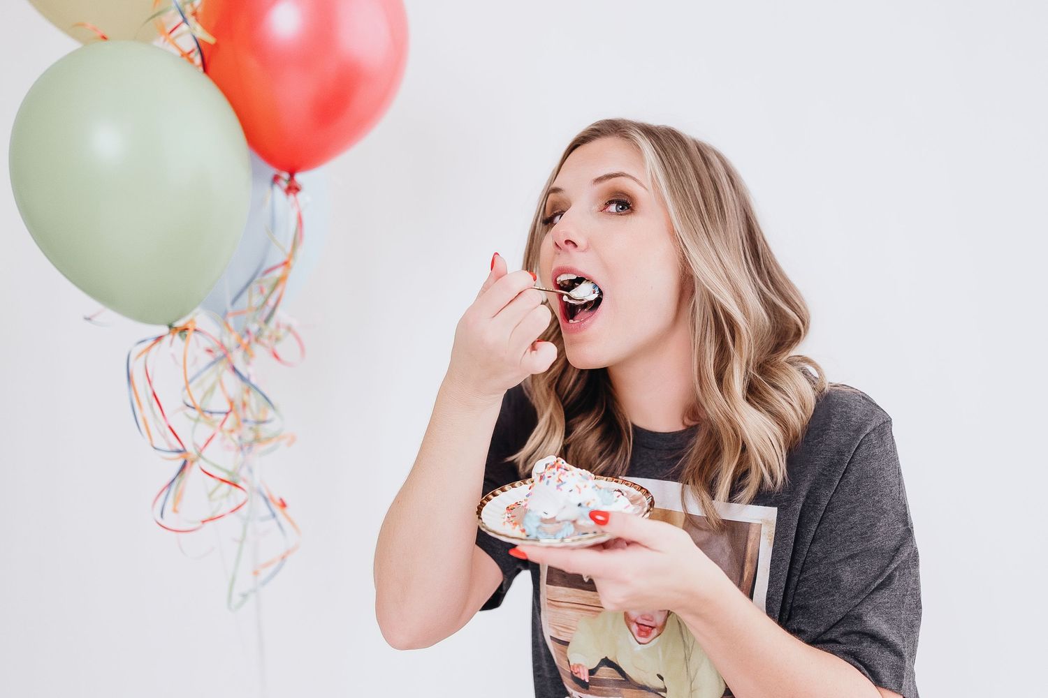Celebratory photoshoot with cake and colorful party balloons.