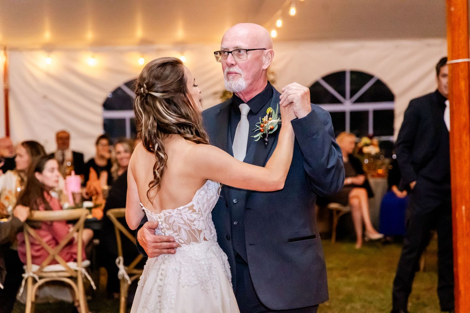 Wedding reception dance in a white tent with string lights overhead.