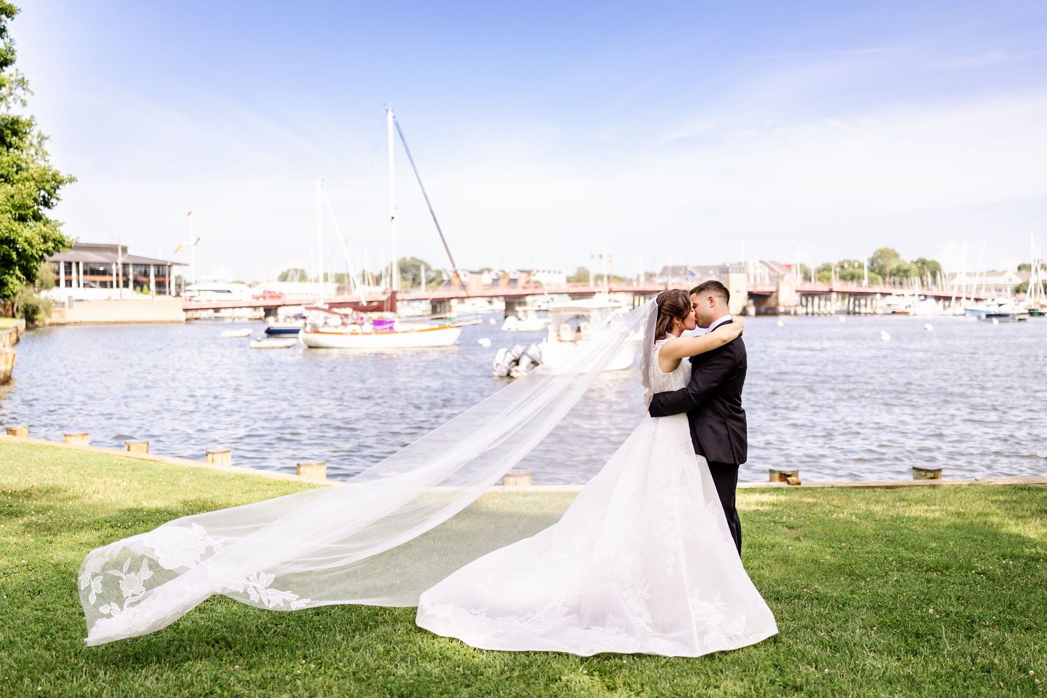 Wedding dress train flowing in the wind against waterfront marina backdrop.
