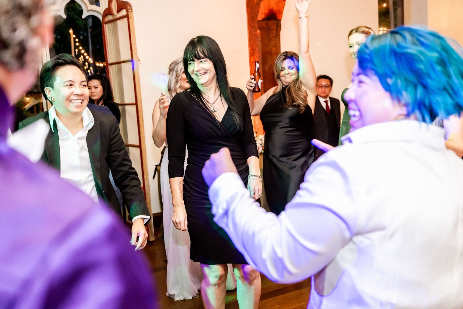 Guests dancing and celebrating at indoor party with performer in white outfit.