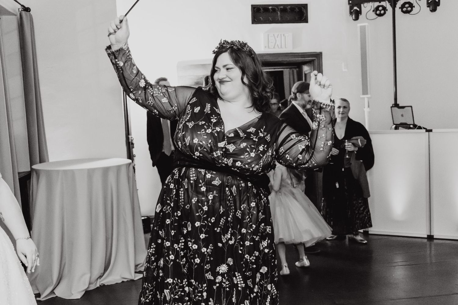 Dancing celebrant during a wedding reception in a black floral print dress.