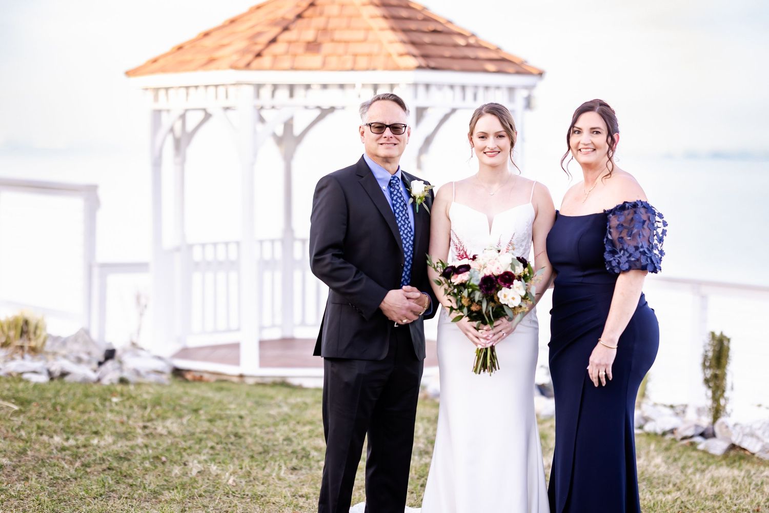 Wedding party poses together outdoors in formal attire with blue and white color scheme.