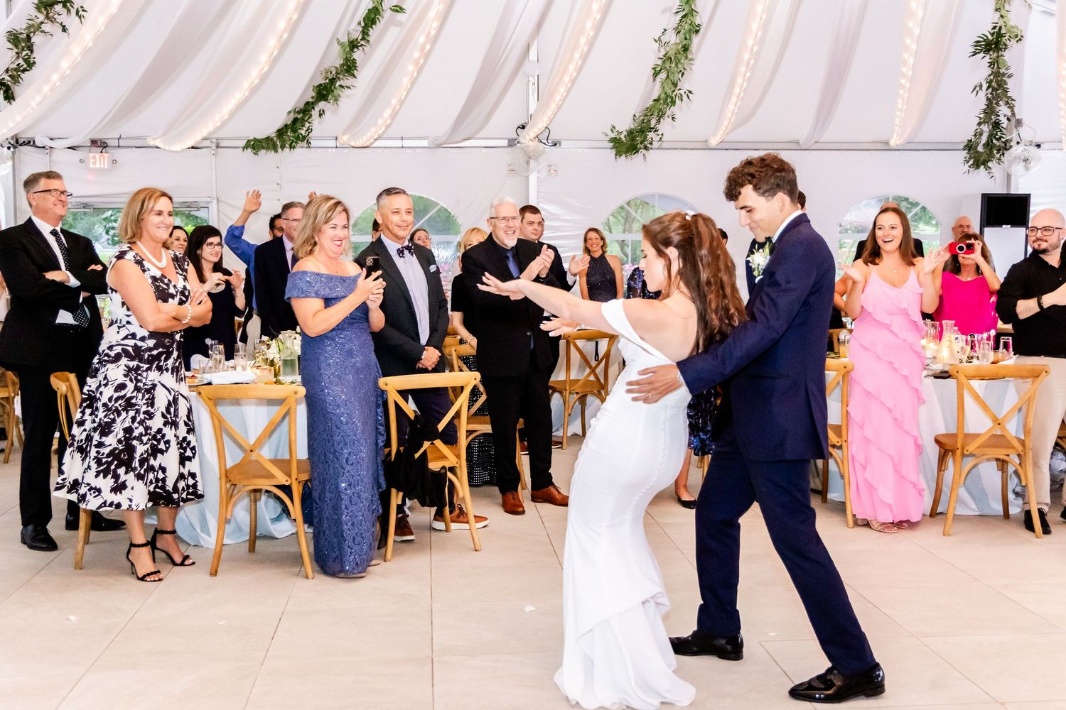 Wedding guests watch the couple's first dance in a decorated tent venue.