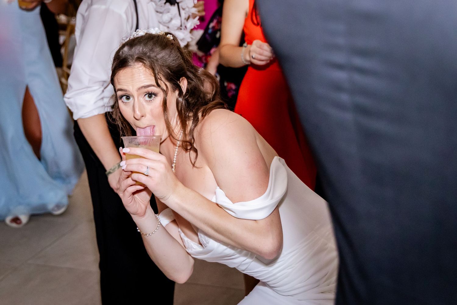 A person in a white dress enjoys a drink during a wedding reception celebration.