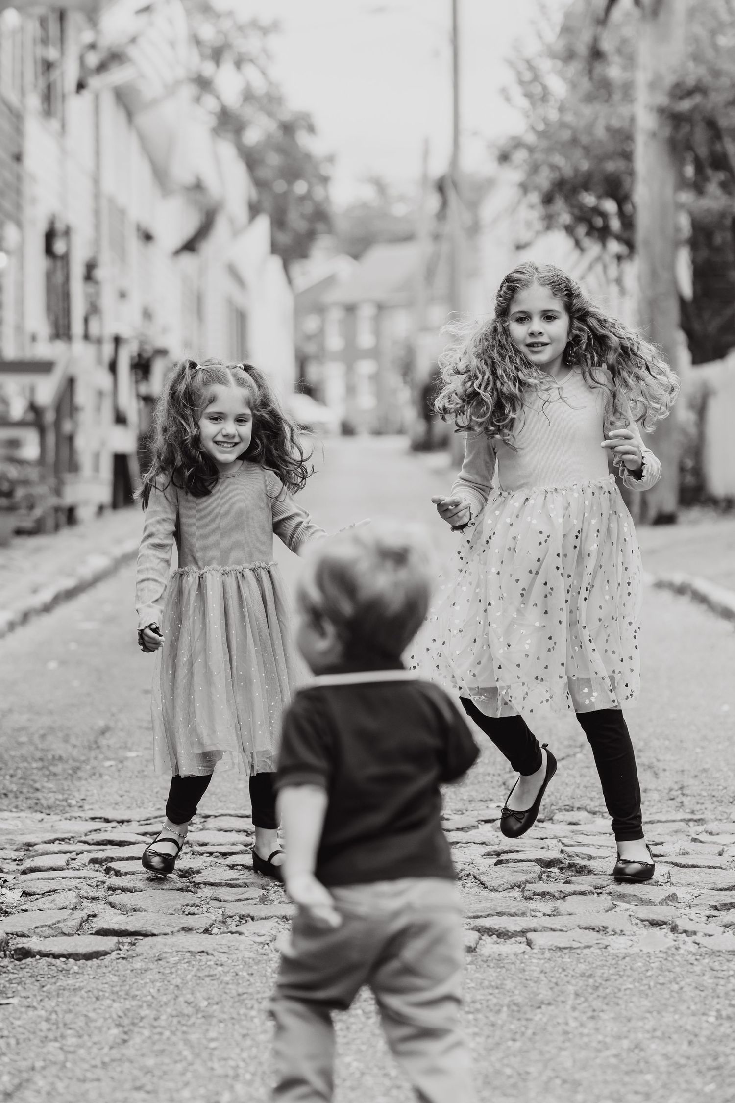 A sequence of black and white photos showing children playing and running on a cobblestone street.