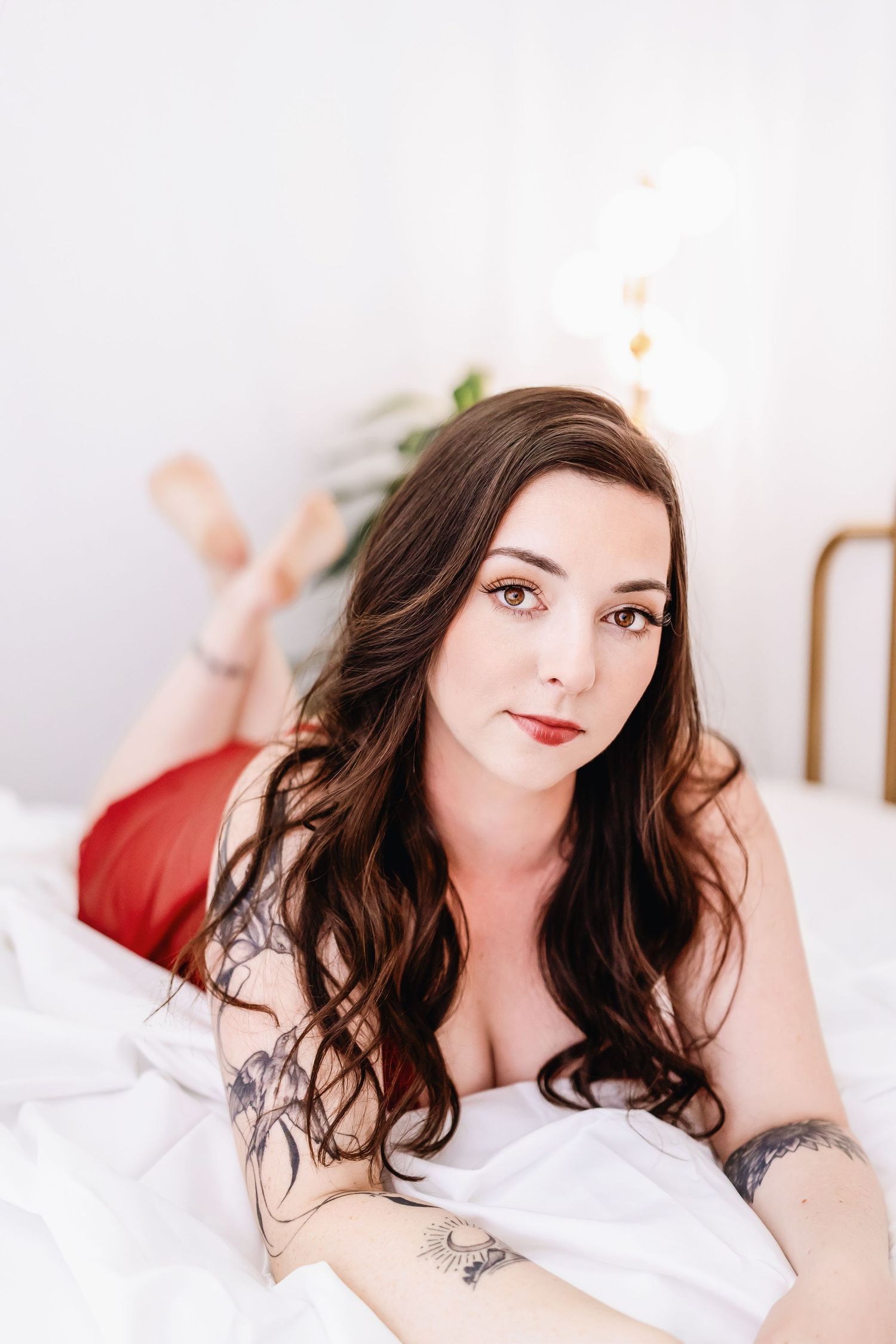 Artistic boudoir photography series in white bedding showing a brunette woman in romantic soft lighting.