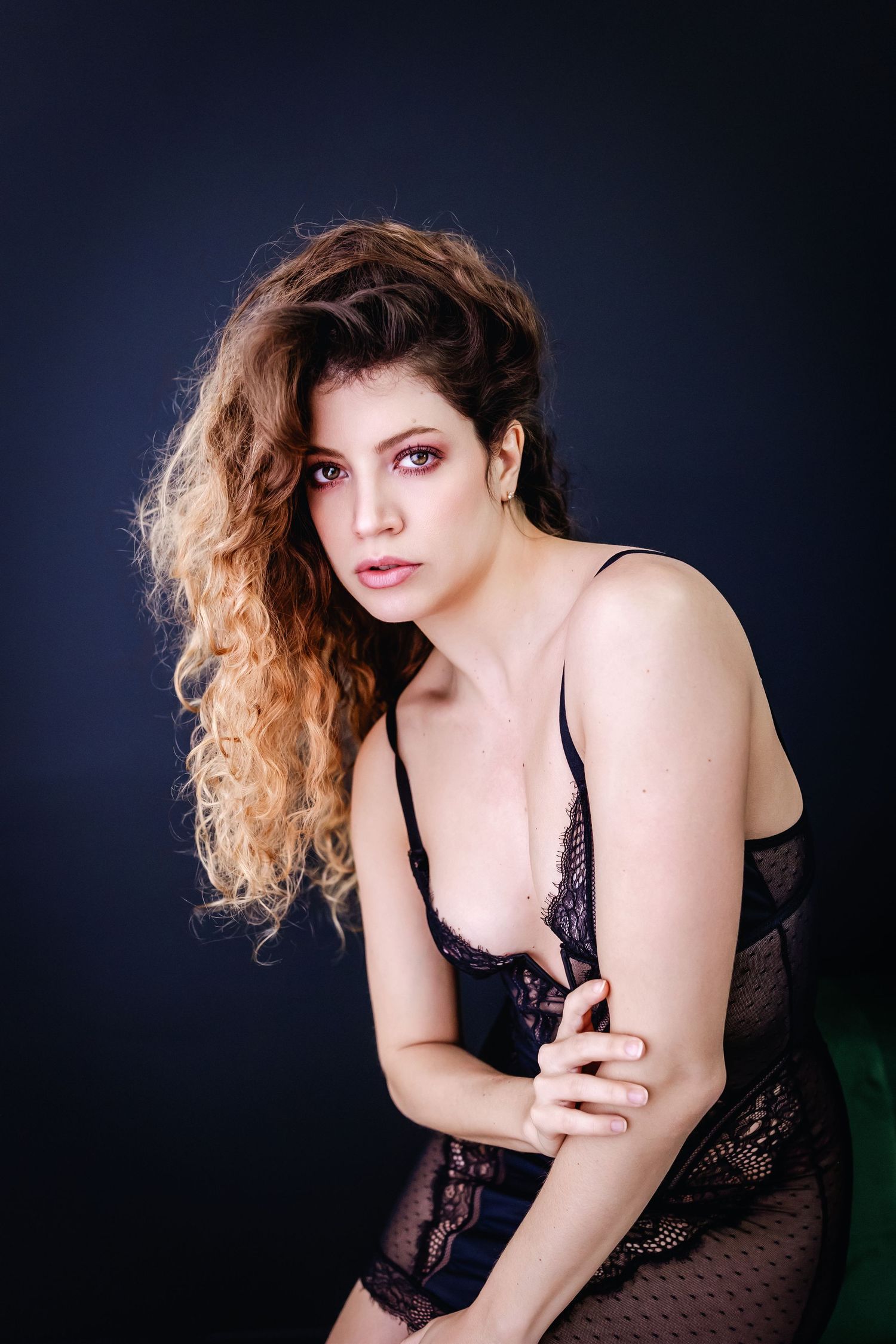 Artistic boudoir photography series featuring moody lighting and black lace lingerie against dark background.