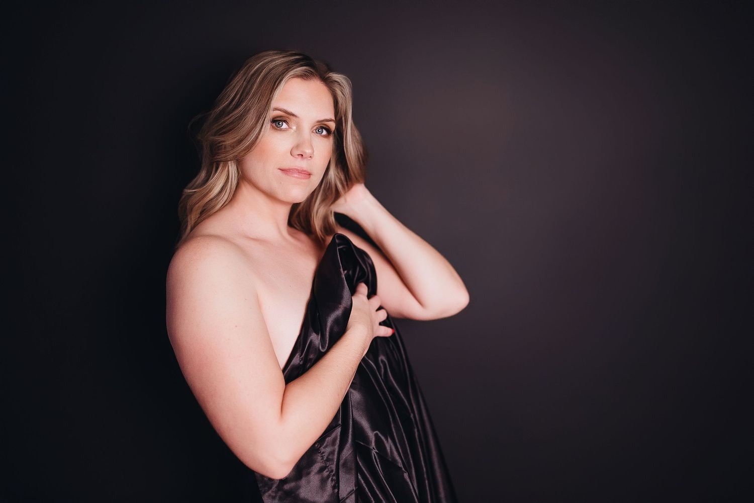 A series of artistic boudoir portraits showing a woman in dramatic lighting against a dark background.