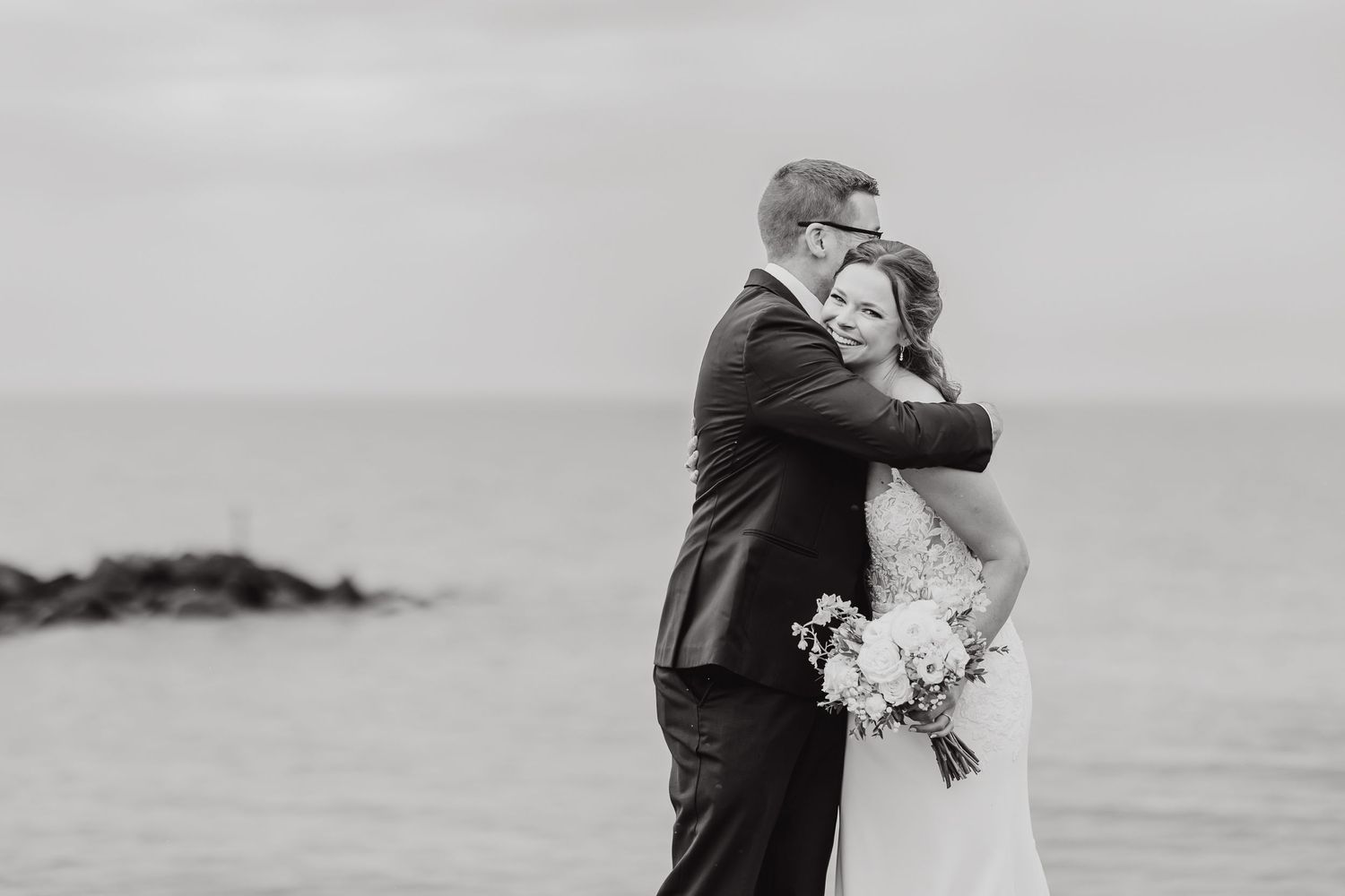 Black and white wedding photography sequence showing intimate moments between a couple on a beach.