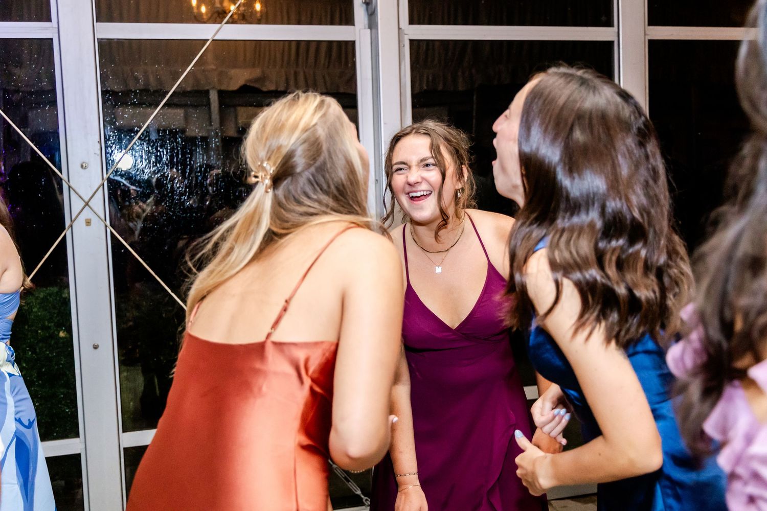 Wedding guests dancing and mingling at an evening reception with colorful lighting effects.