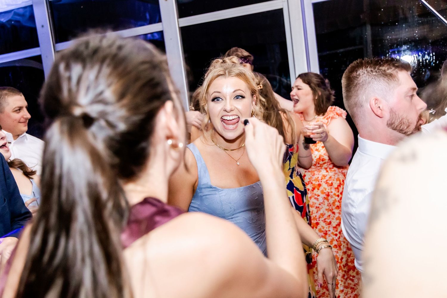 Energetic crowd of wedding guests dancing and celebrating on the dance floor.