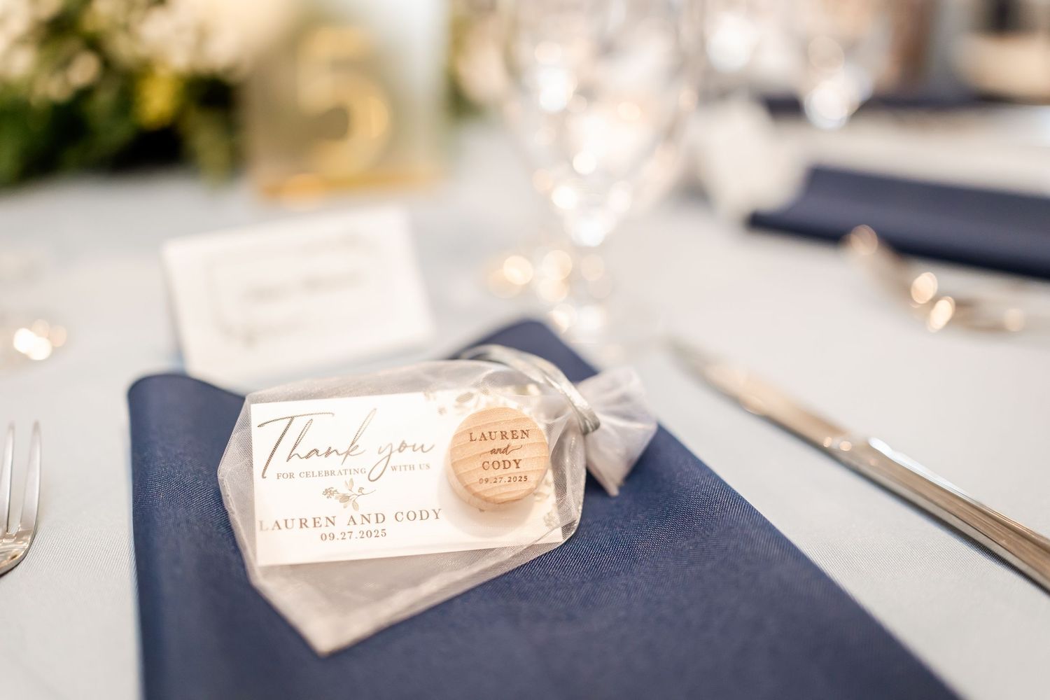 Wedding place setting with navy blue napkin and thank you tag on elegant table.