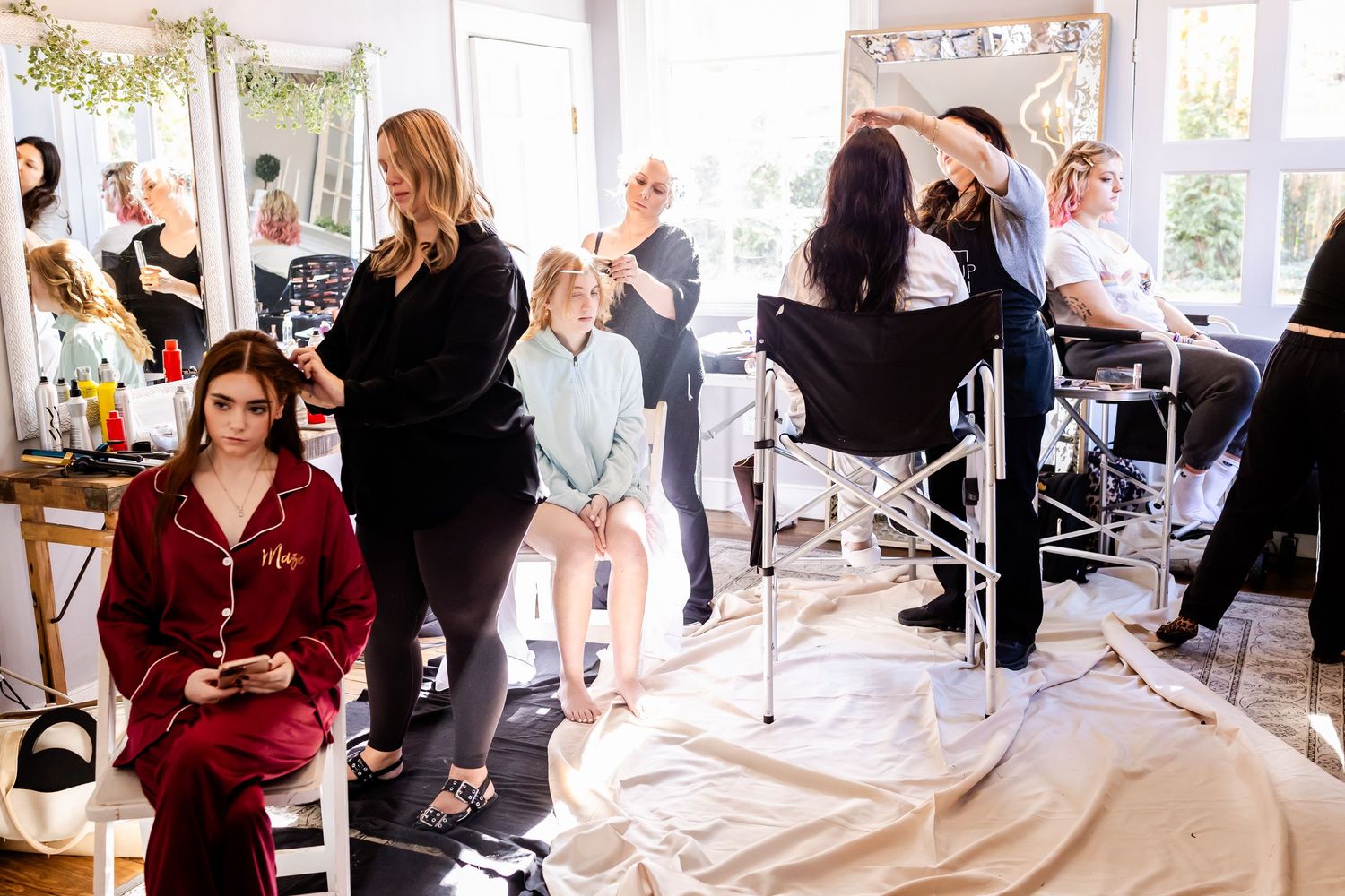 A group of people gather in a bright modern salon space with stylists working at various stations.
