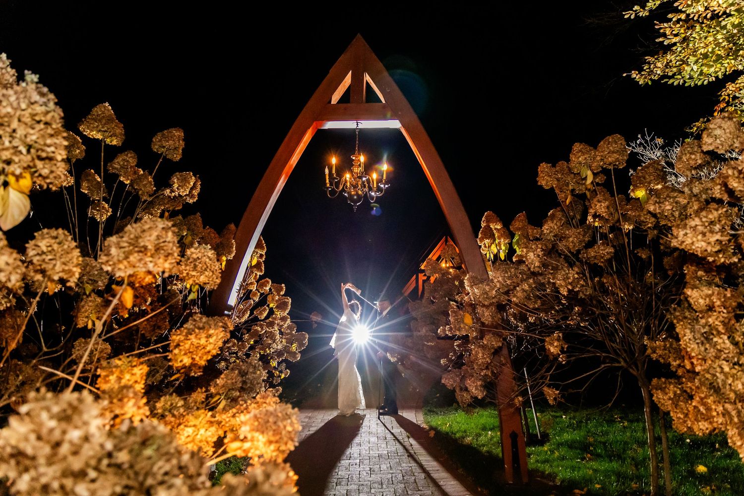 Illuminated wooden chapel structure at night with glowing lights and autumn trees.