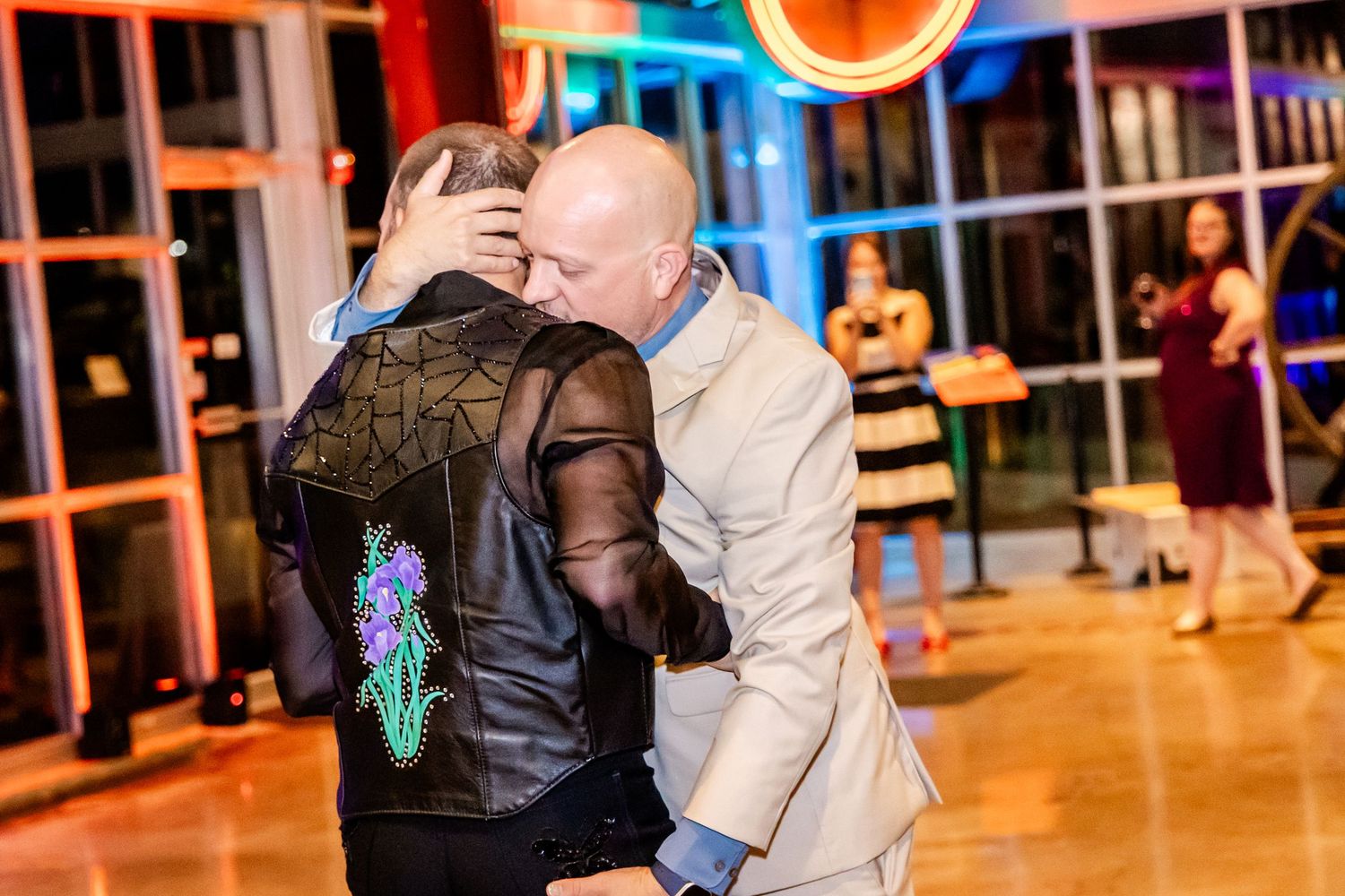 A couple dances together at an indoor venue with glowing orange lights and Halloween decorations in the background.