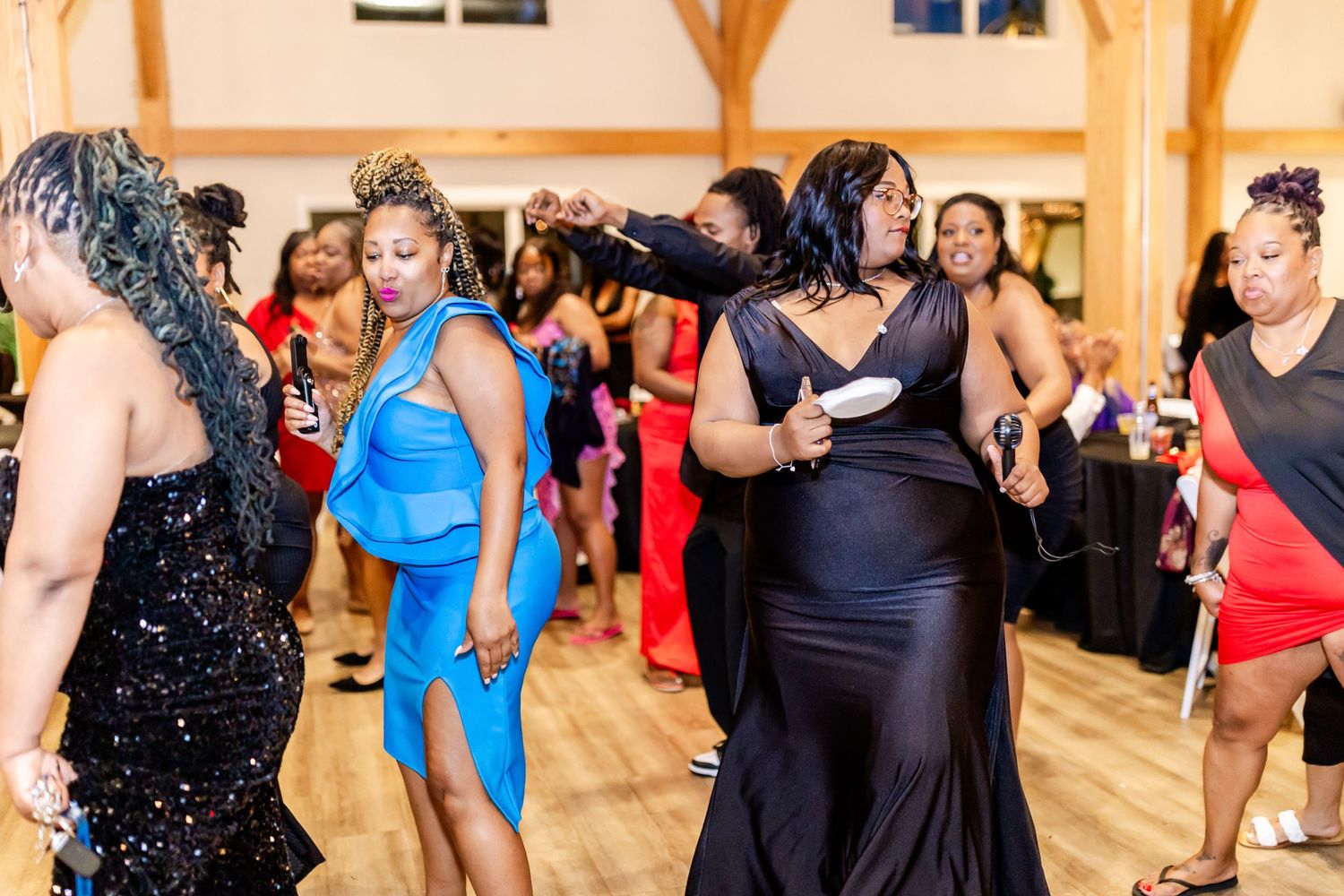Elegant party guests dancing together in formal attire on a wooden dance floor.