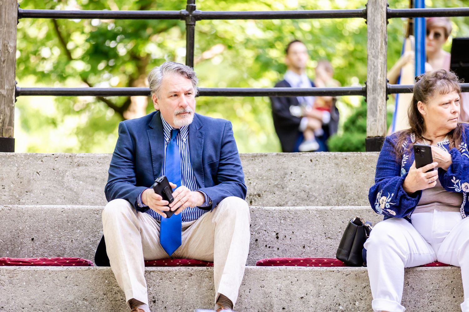 Guests resting on concrete stadium seating during outdoor event.