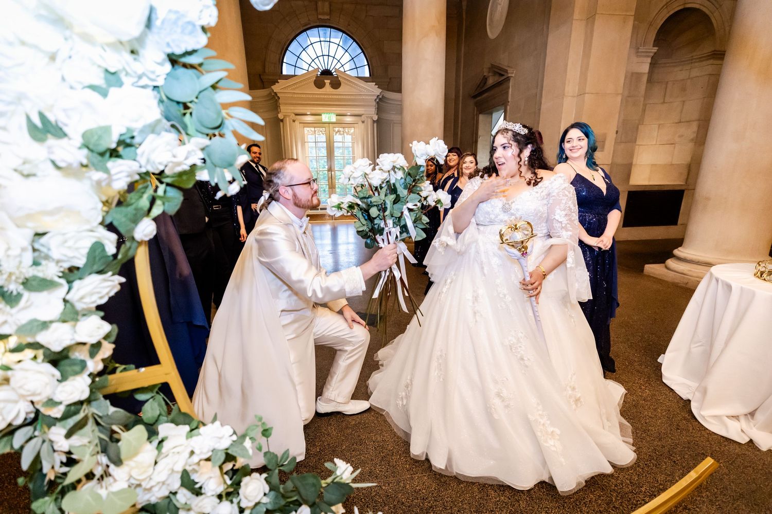 Couple shares romantic moment during wedding ceremony under elegant floral arch and columns.