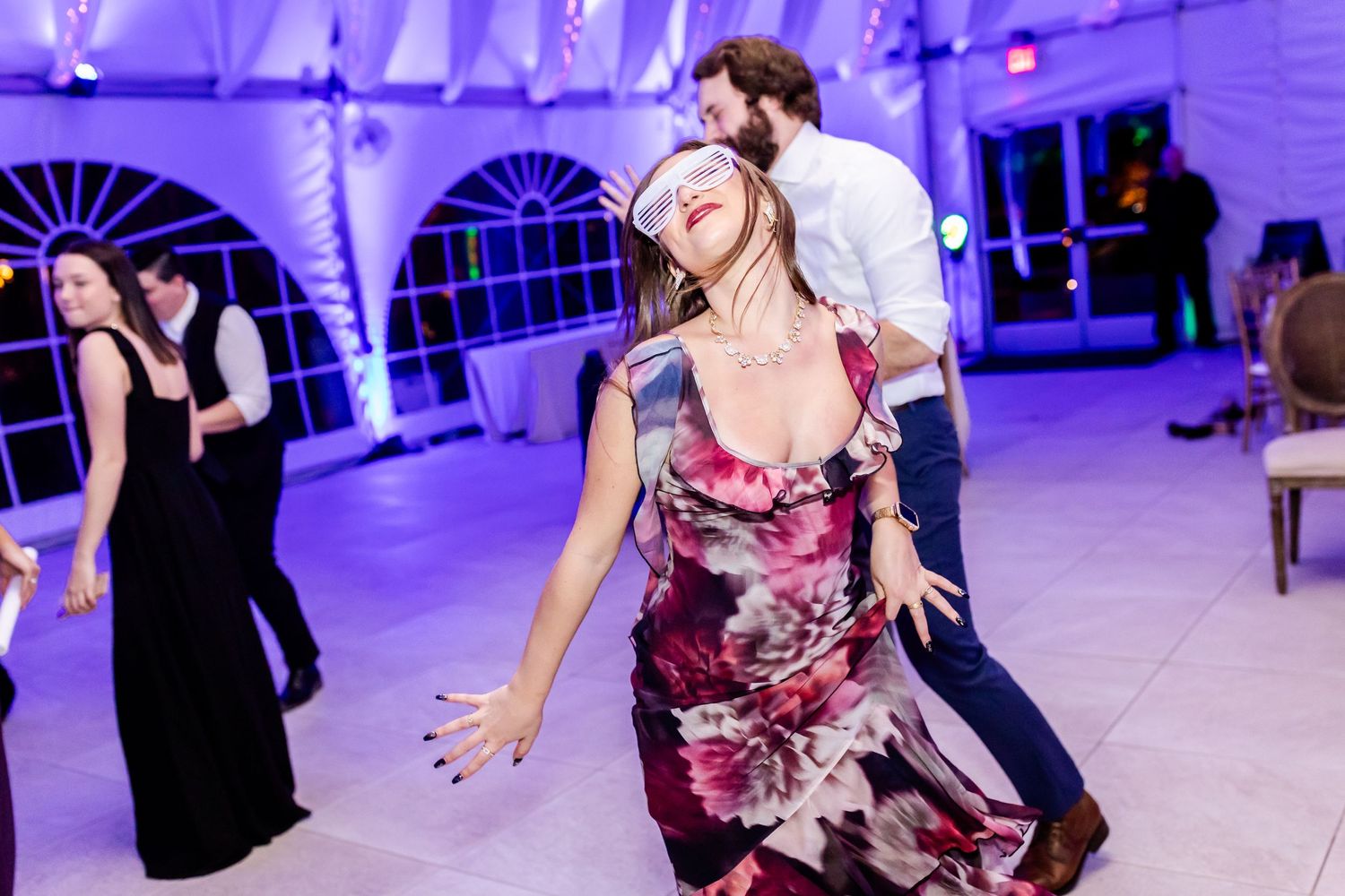Couples dancing and having fun at a wedding reception with purple lighting and draped fabric decor.