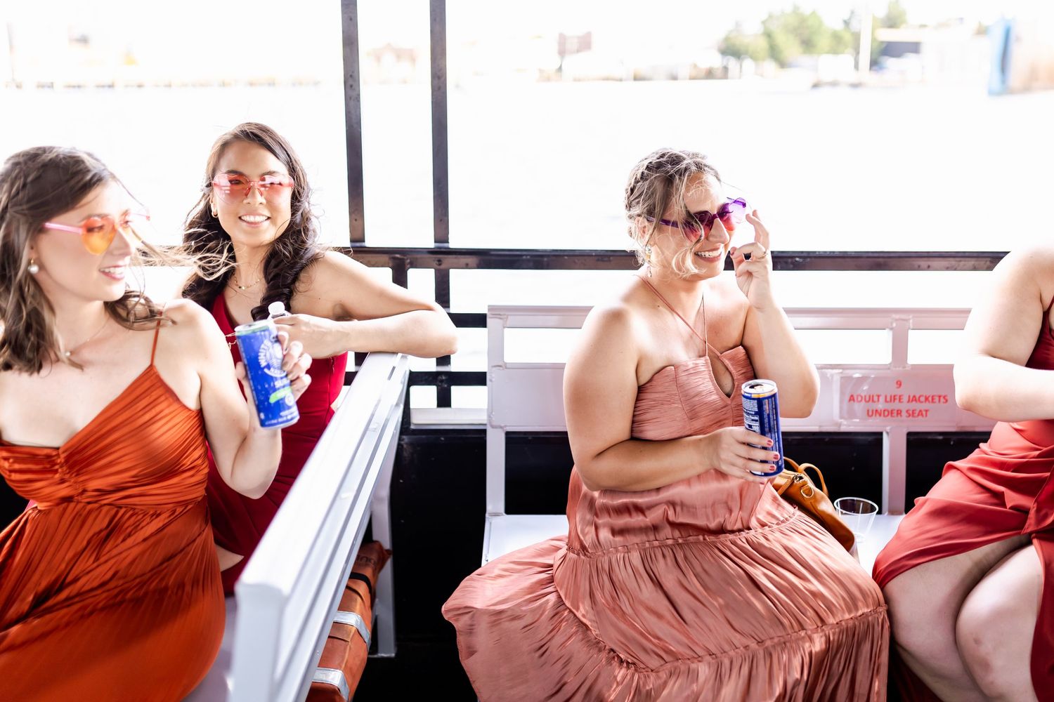 A group in colorful dresses relaxes on a boat deck with drinks during a celebration.