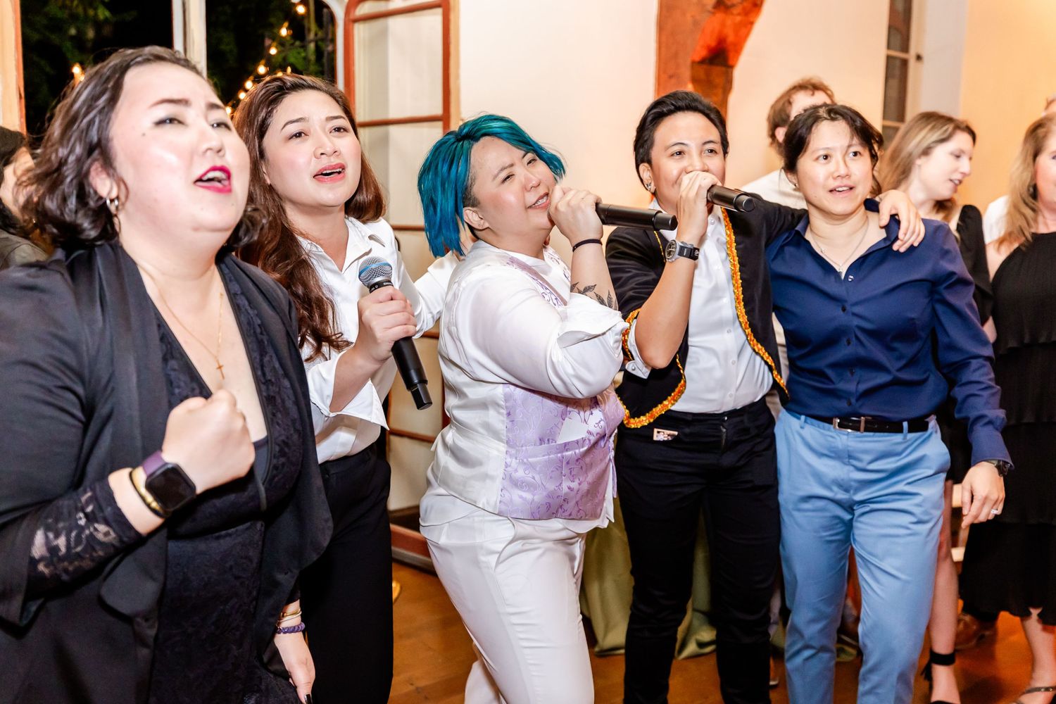 Enthusiastic group singing and dancing together during an indoor celebration.