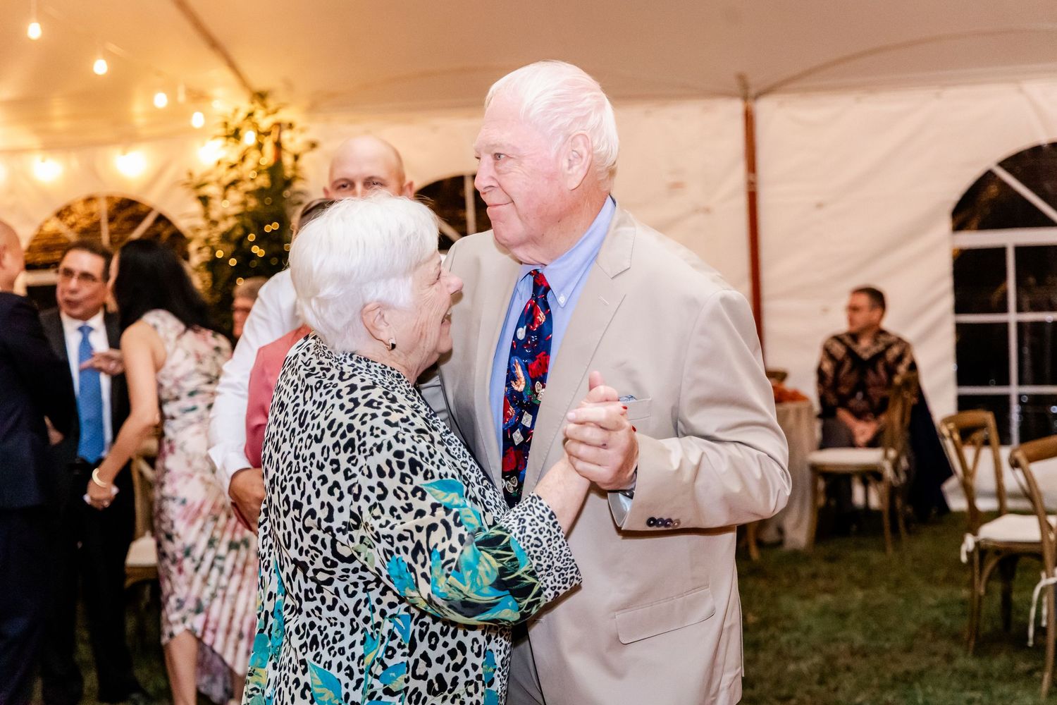 Guests enjoying a lively dance party under a white wedding tent with string lights.