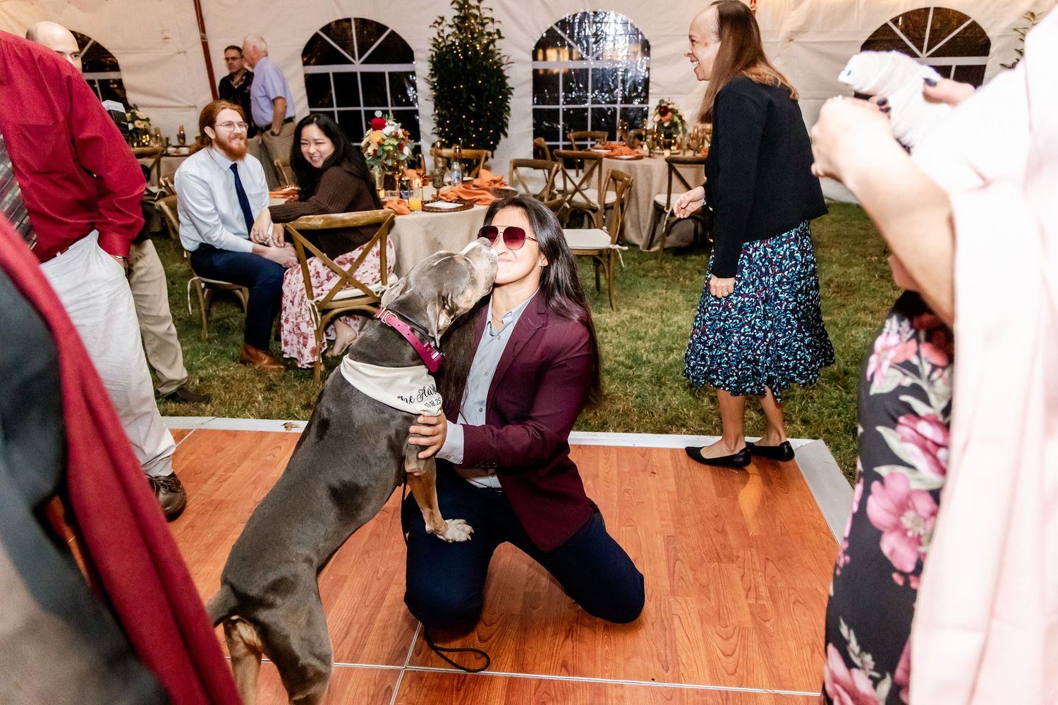 Wedding reception guests dancing and socializing on a wooden dance floor under a tent.