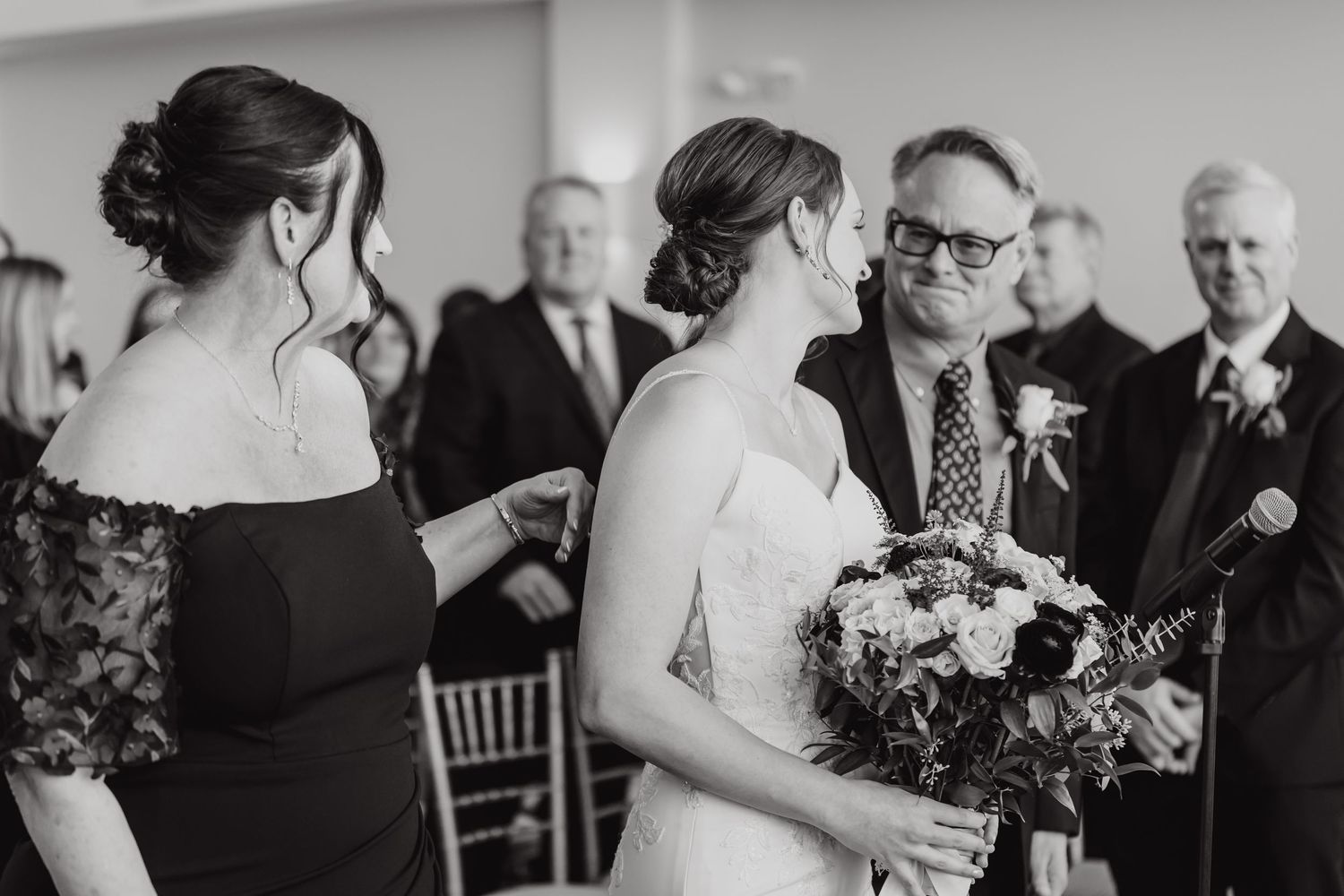 Black and white photo of wedding guests seated at tables during an elegant indoor reception.