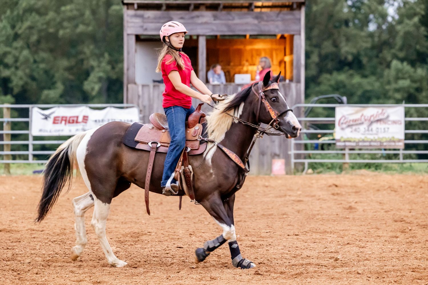 Western rider practices barrel racing techniques in outdoor arena.