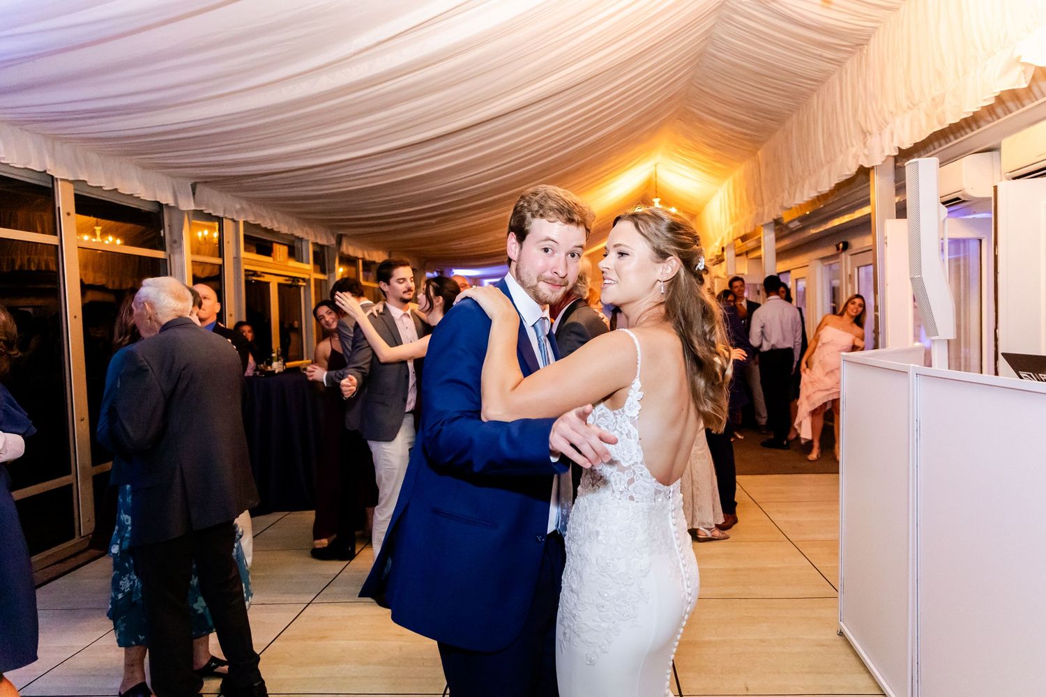 Elegant wedding reception under white tent with couples dancing on the dance floor.