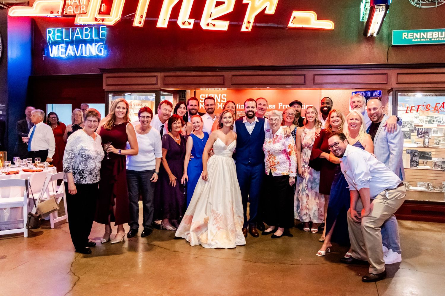 Wedding party poses for a group photo in front of a retro diner sign.