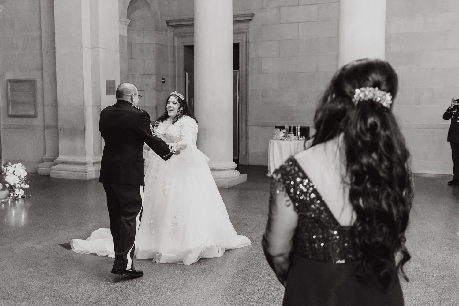 Wedding dance in monochrome captures movement in an elegant columned ballroom.