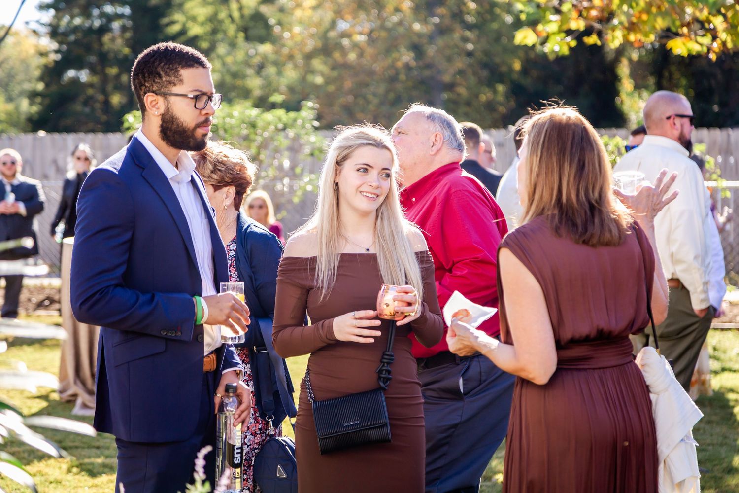 Wedding reception guests mingling and socializing outdoors during golden hour.