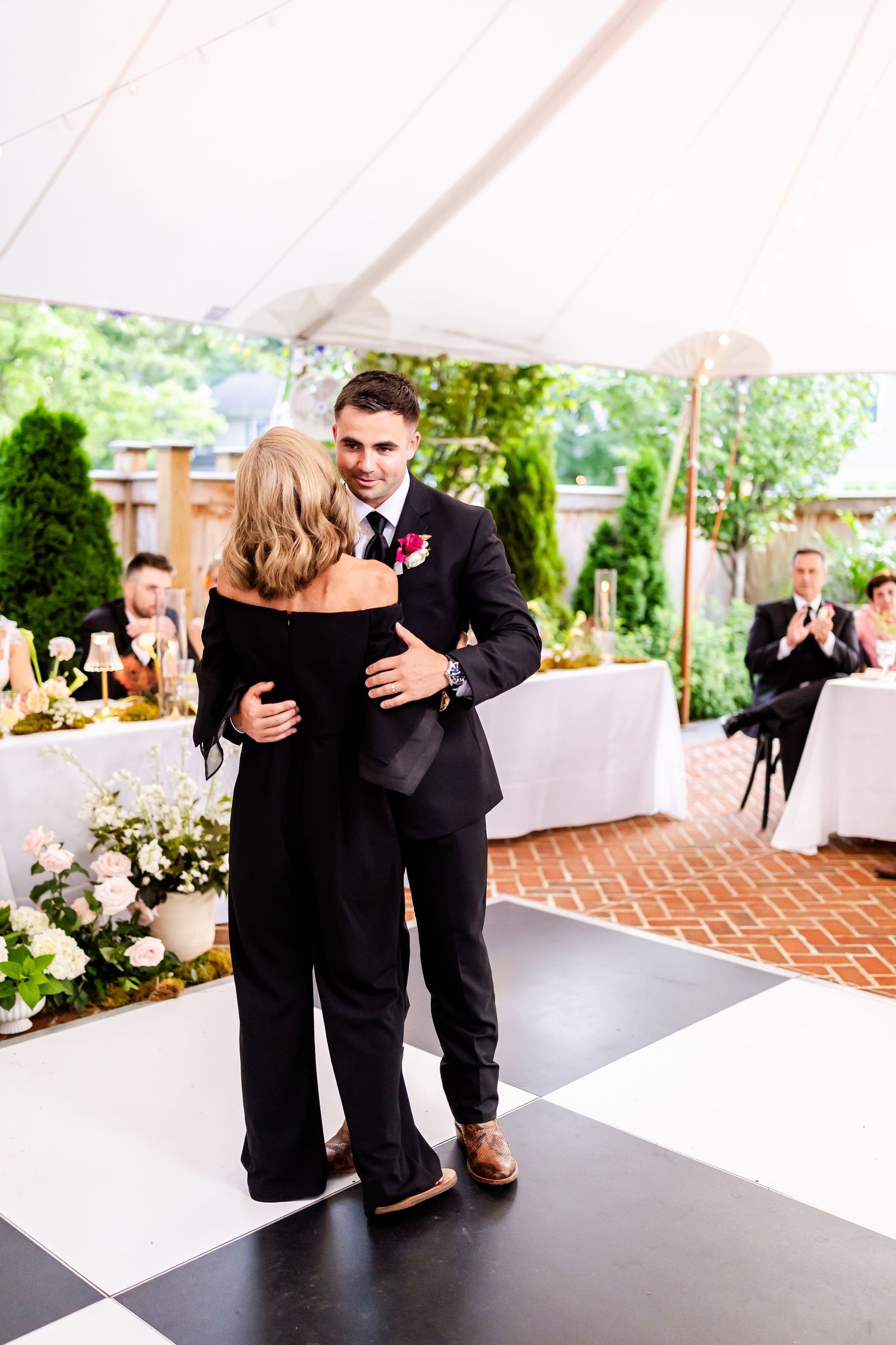 Wedding party dancing on a black and white checkered dance floor at an outdoor reception.