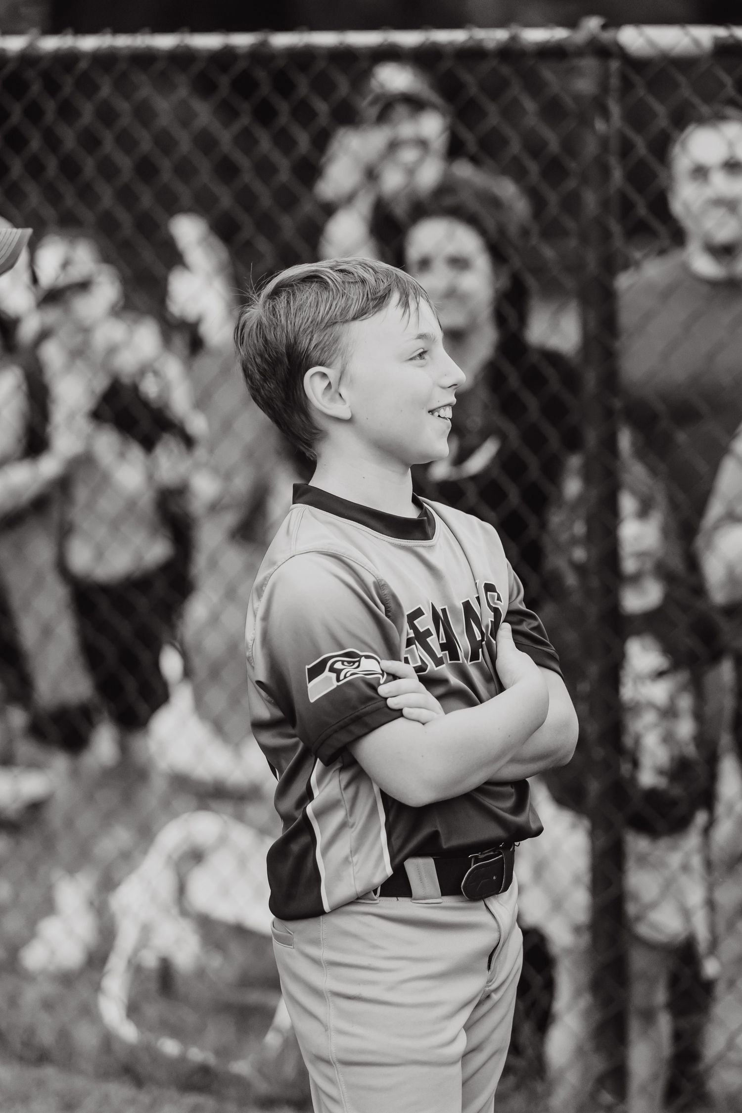 Young baseball player in uniform practicing batting stance in black and white.