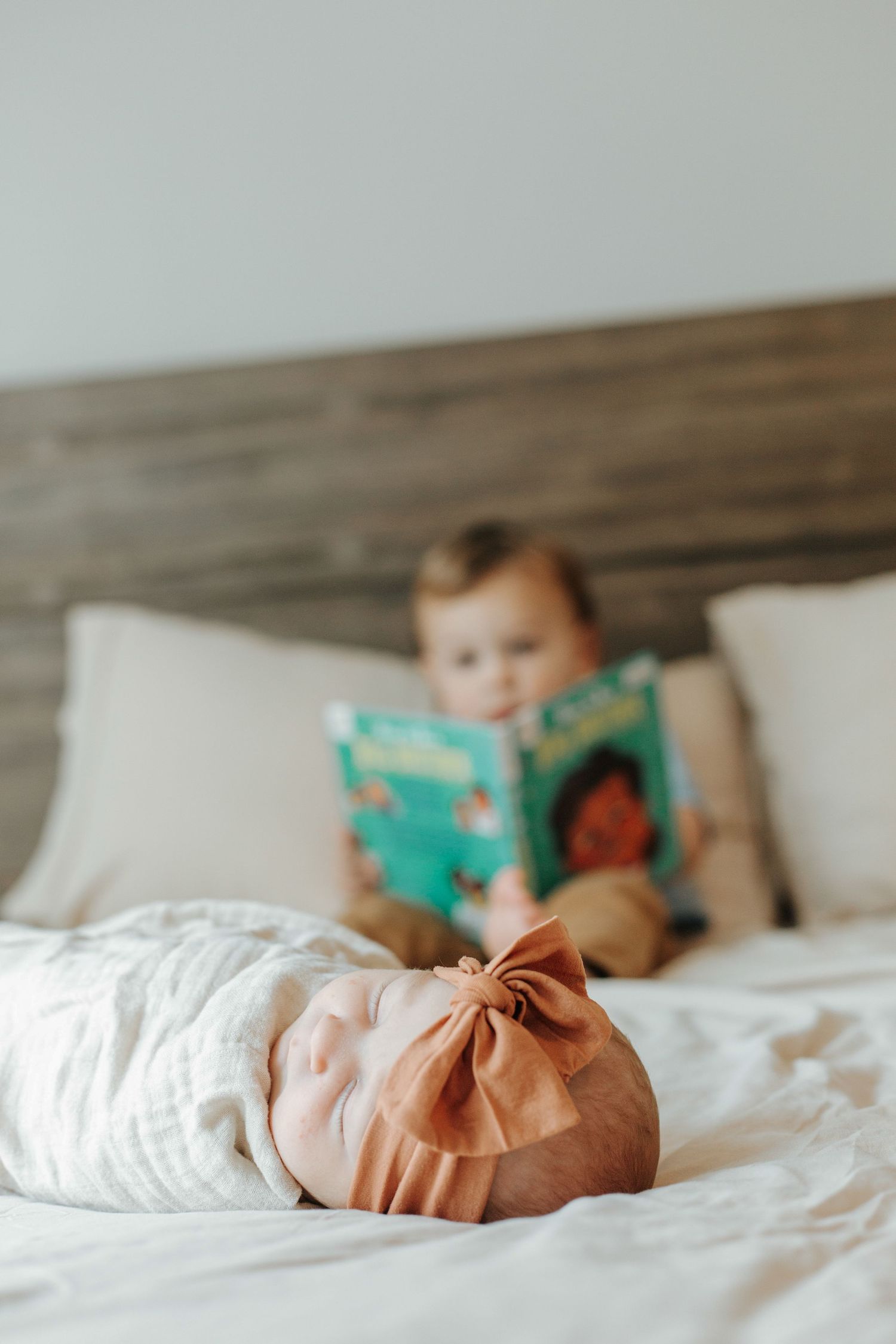 A cozy bedroom scene with soft white bedding and a turquoise book in view.