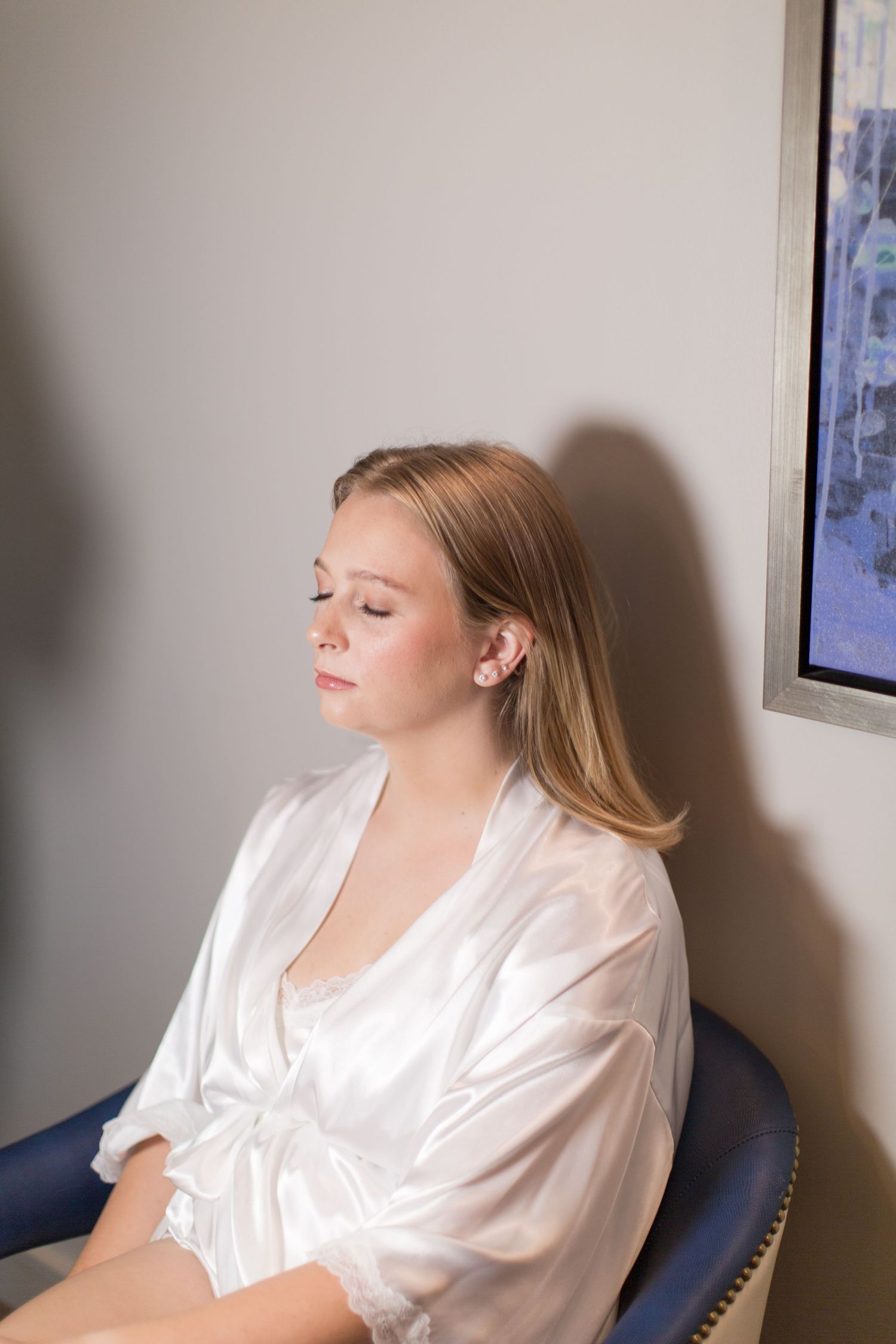 Preparation photos in white silk robe against grey wall.