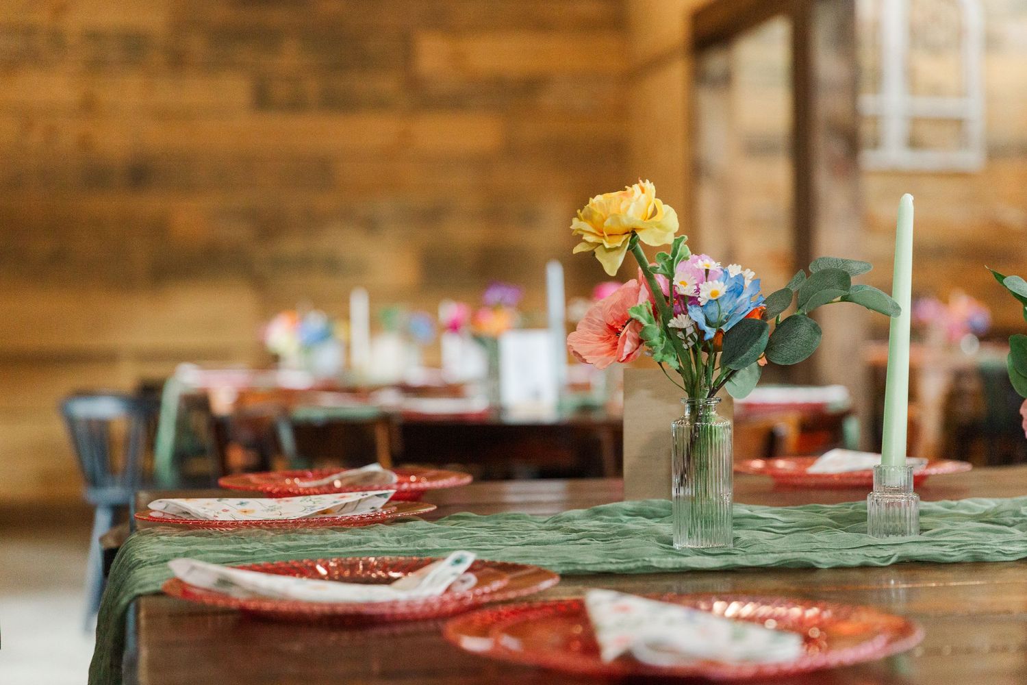 Rustic wedding reception table setting with brick walls and floral centerpieces.