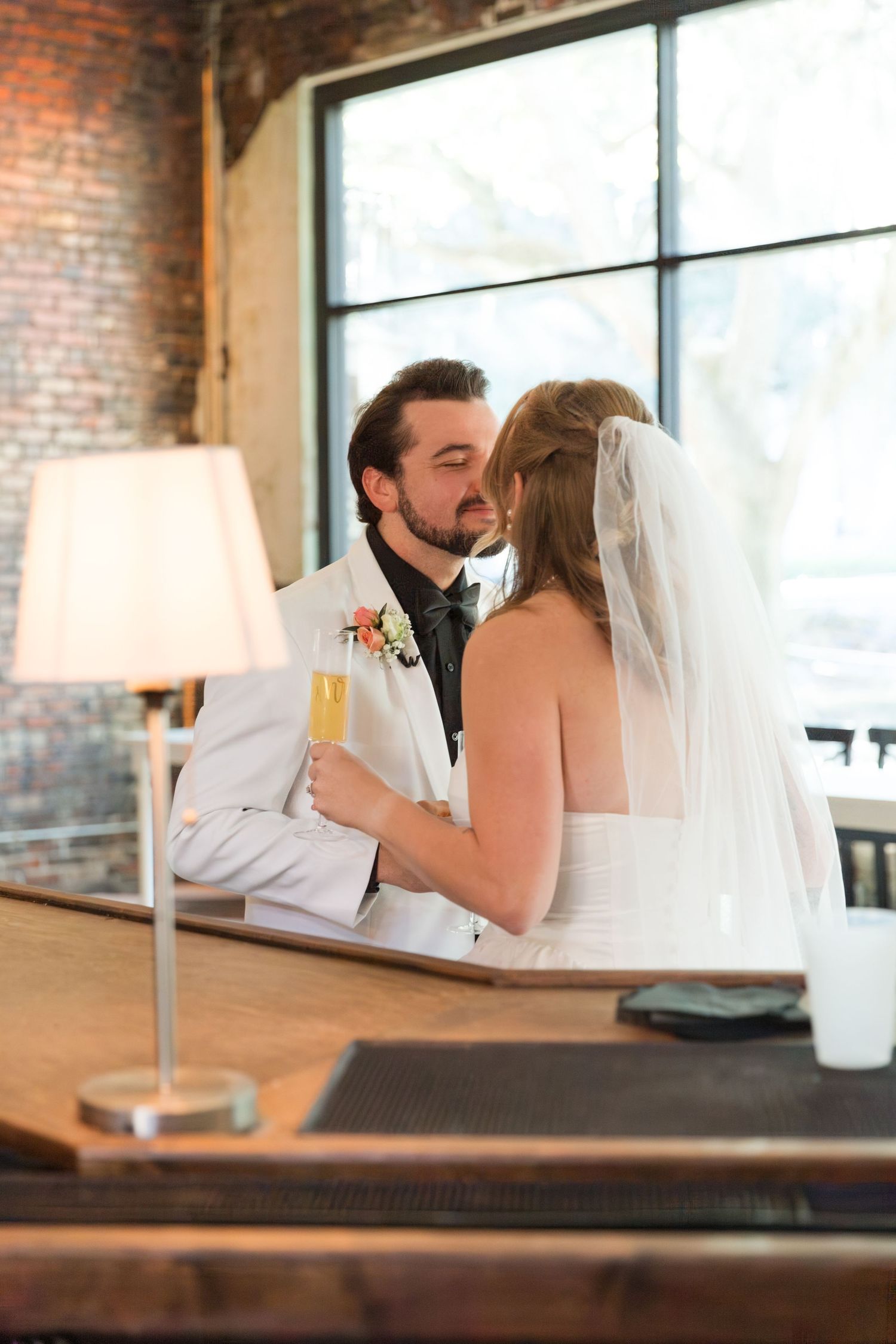 Wedding couple sharing intimate moment at rustic brick venue.