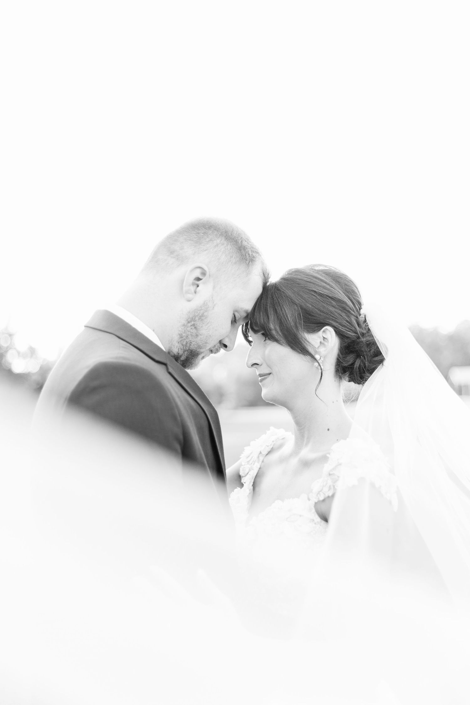 Romantic wedding couple shares intimate moments in a soft-focus outdoor setting.