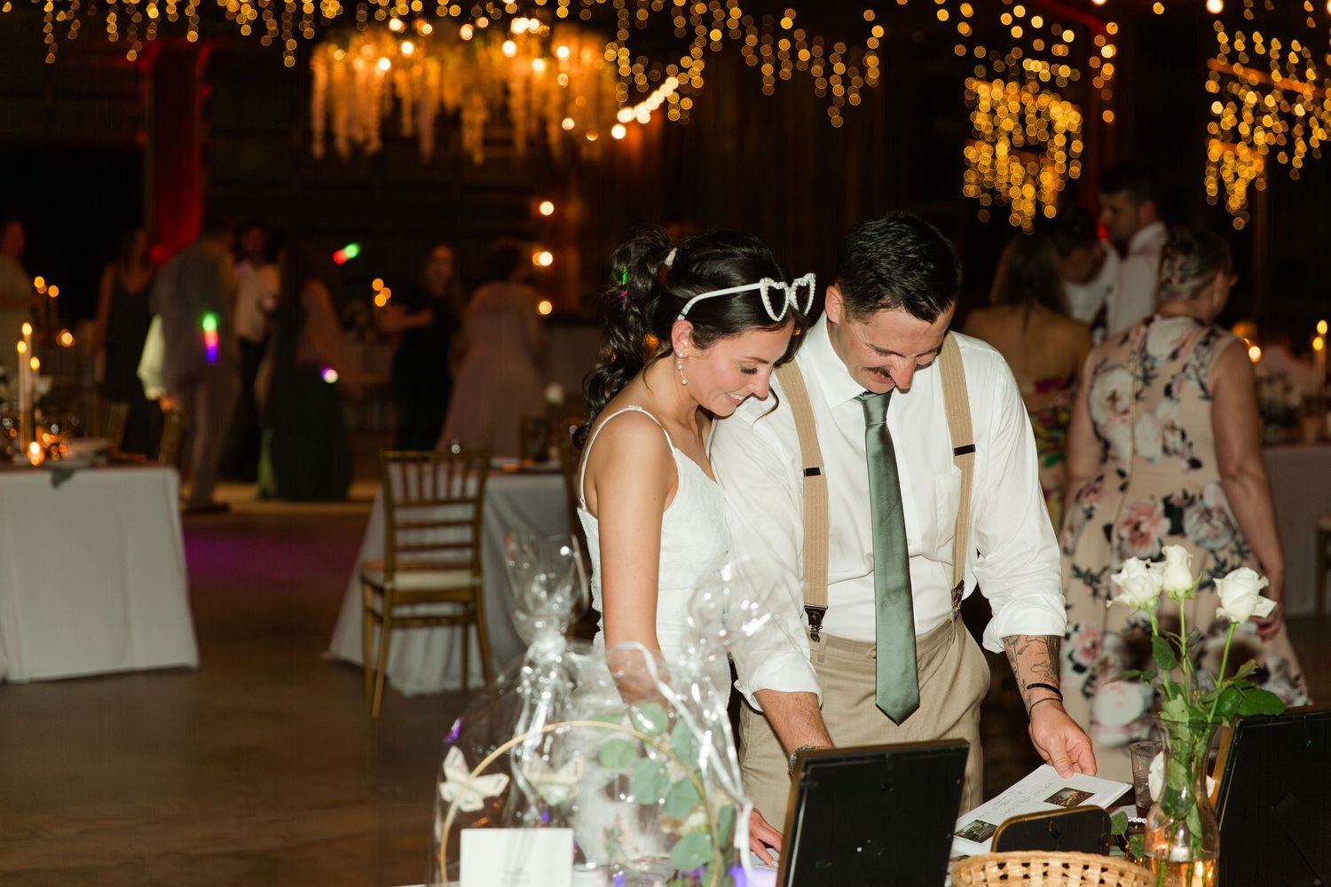 Romantic wedding reception table setting with glowing candles and elegant floral centerpieces in a dimly lit venue.