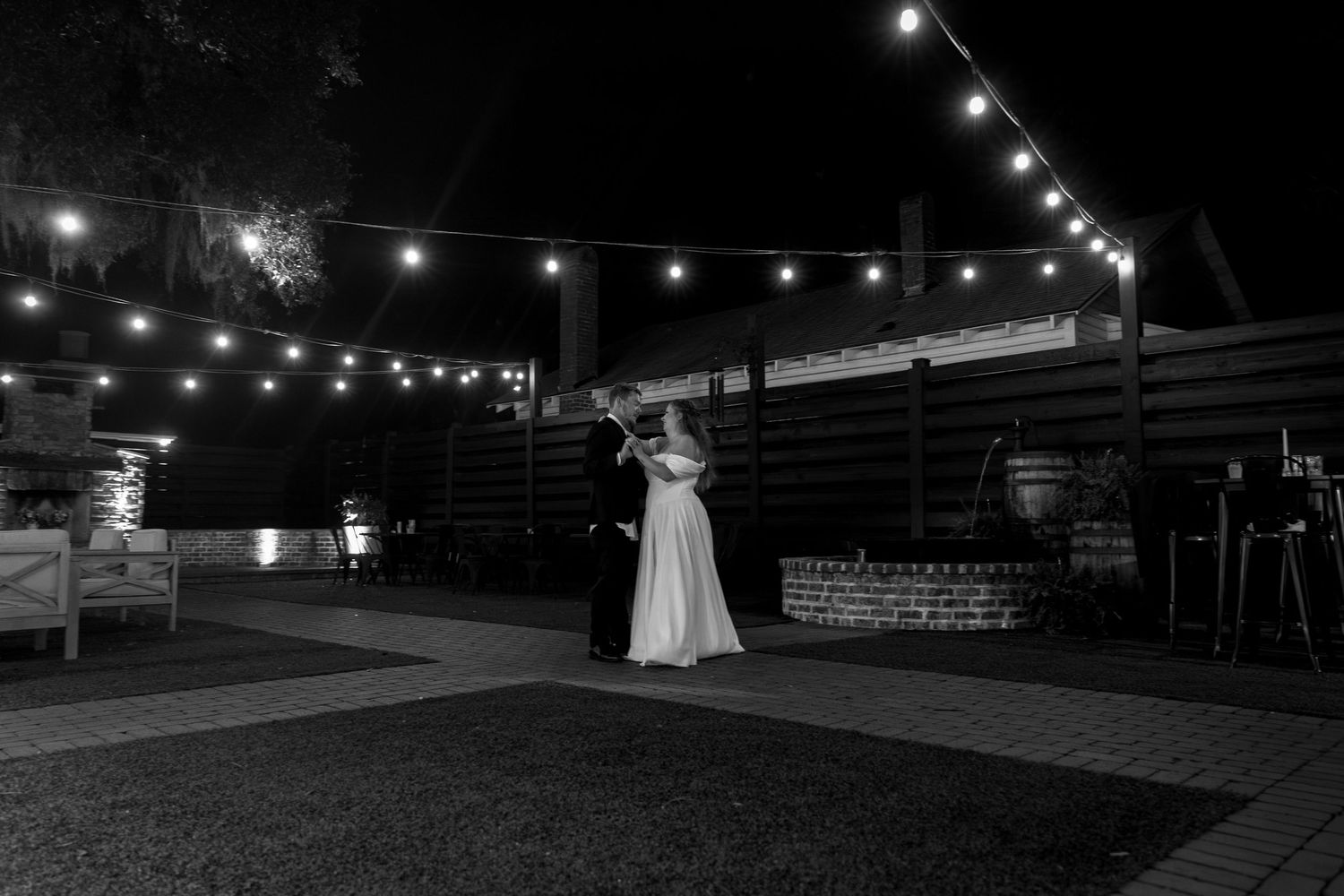 A romantic outdoor wedding venue at night illuminated by string lights creating a magical atmosphere.