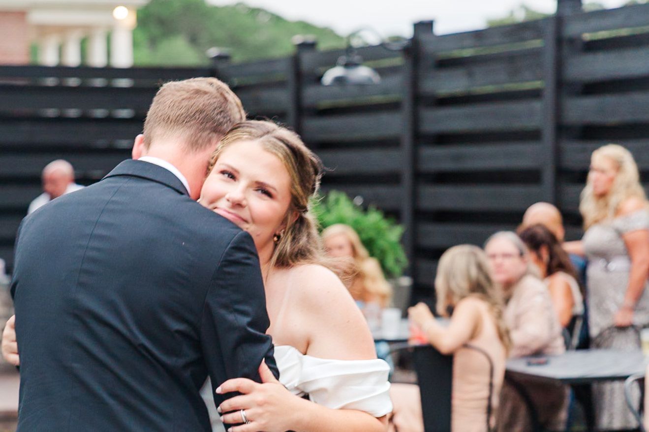 Newlyweds embracing during outdoor wedding reception dance.
