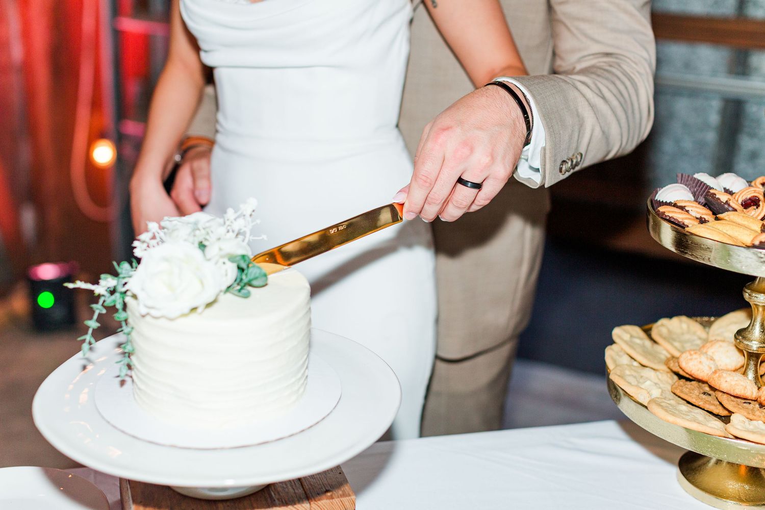 Wedding cake cutting sequence showing white tiered cake with floral decorations at reception.