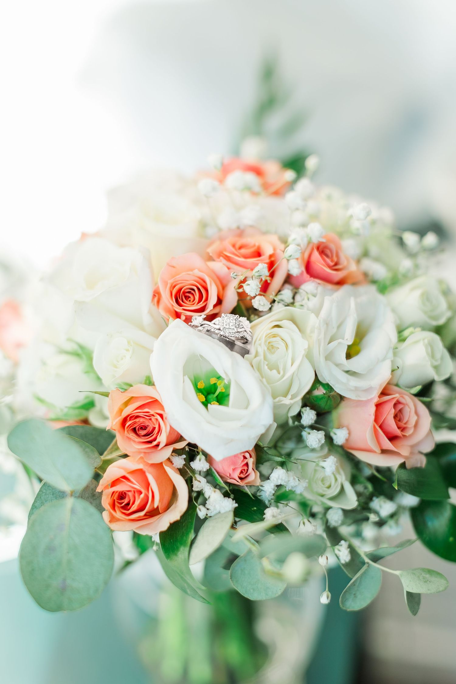 Beautiful floral arrangement with coral roses and white flowers with greenery.